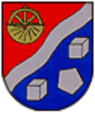 Wappen durch silbernen schräglinken Wellenbalken geteilt, oben in Rot zweigeteiltes goldenes Rad, als halbe Haspel nach oben und halben Mahlstein nach unten weisend. Unten in Blau in Halbkreisform angeordnet links oben anfangend: Ein silberner Würfel, ein silbernes Fünfeck und ein 2. silberner Würfel.