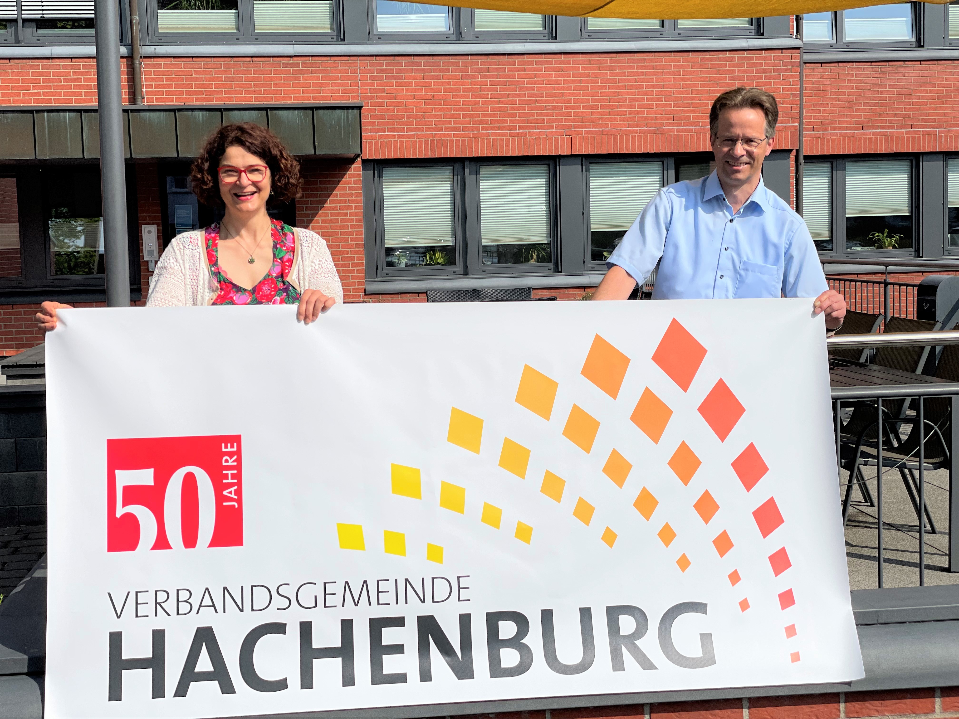 Bürgermeisterin Gabriele Greis und Erster Beigeordneter Marco Dörner halten einen Banner "50 Jahre Verbandsgemeinde Hachenburg"