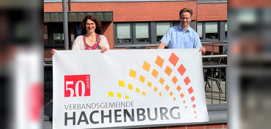 Bürgermeisterin Gabriele Greis und Erster Beigeordneter Marco Dörner halten einen Banner "50 Jahre Verbandsgemeinde Hachenburg"