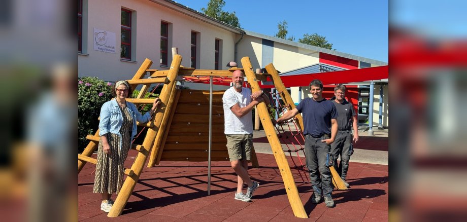 Gruppenfoto von Bürgermeisterin Gabriele Greis, Schulleiter Daniel Busch und Mitarbeiter des Bauhofes (v. l. n. r.) vor dem Sonnensegel der Grundschule Atzelgift-Streithausen