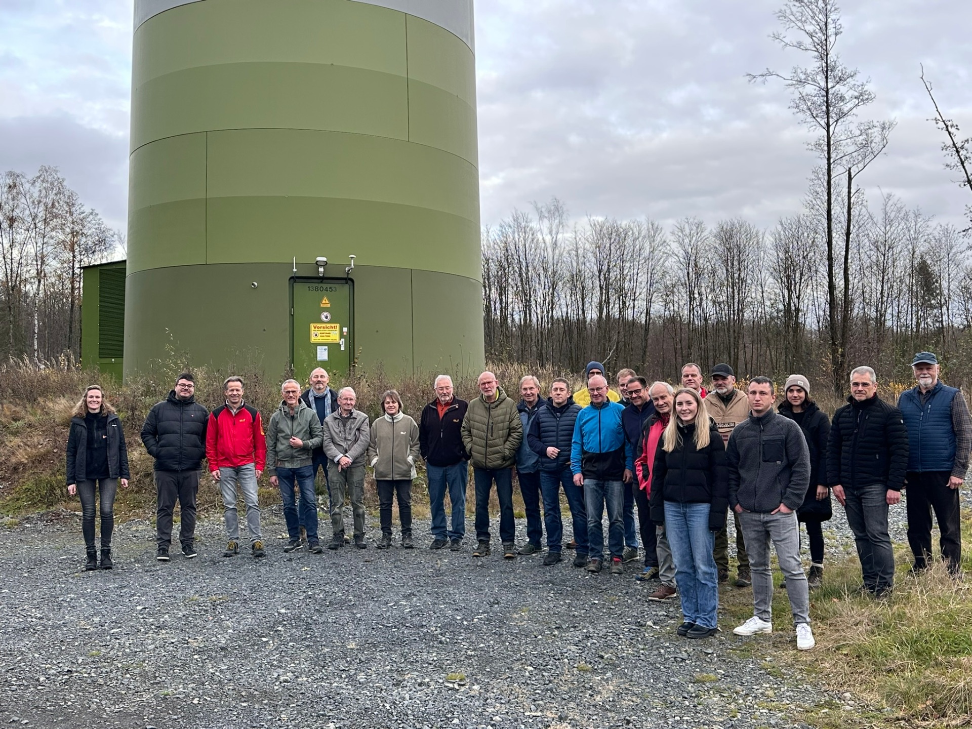 Gruppenbild von mehreren Menschen vor einer Windenergieanlage
