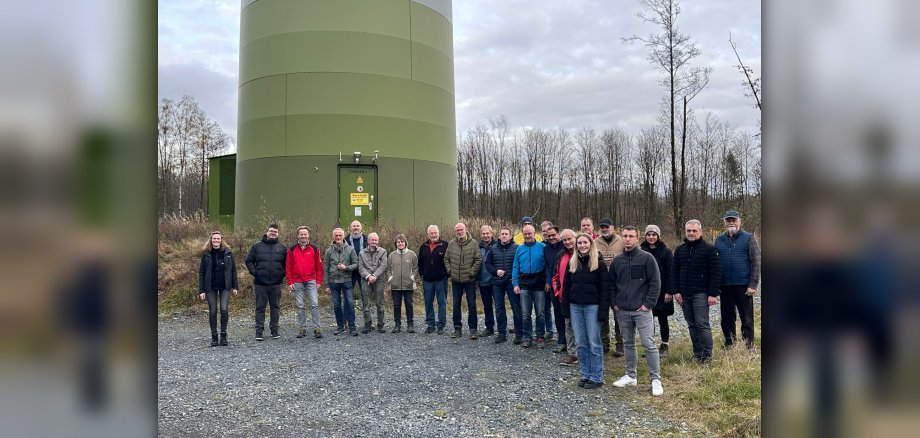 Gruppenbild von mehreren Menschen vor einer Windenergieanlage