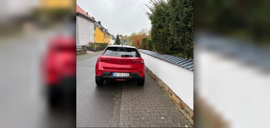 Ein rotes Auto welches falsch am Straßenrand abgestellt wurde