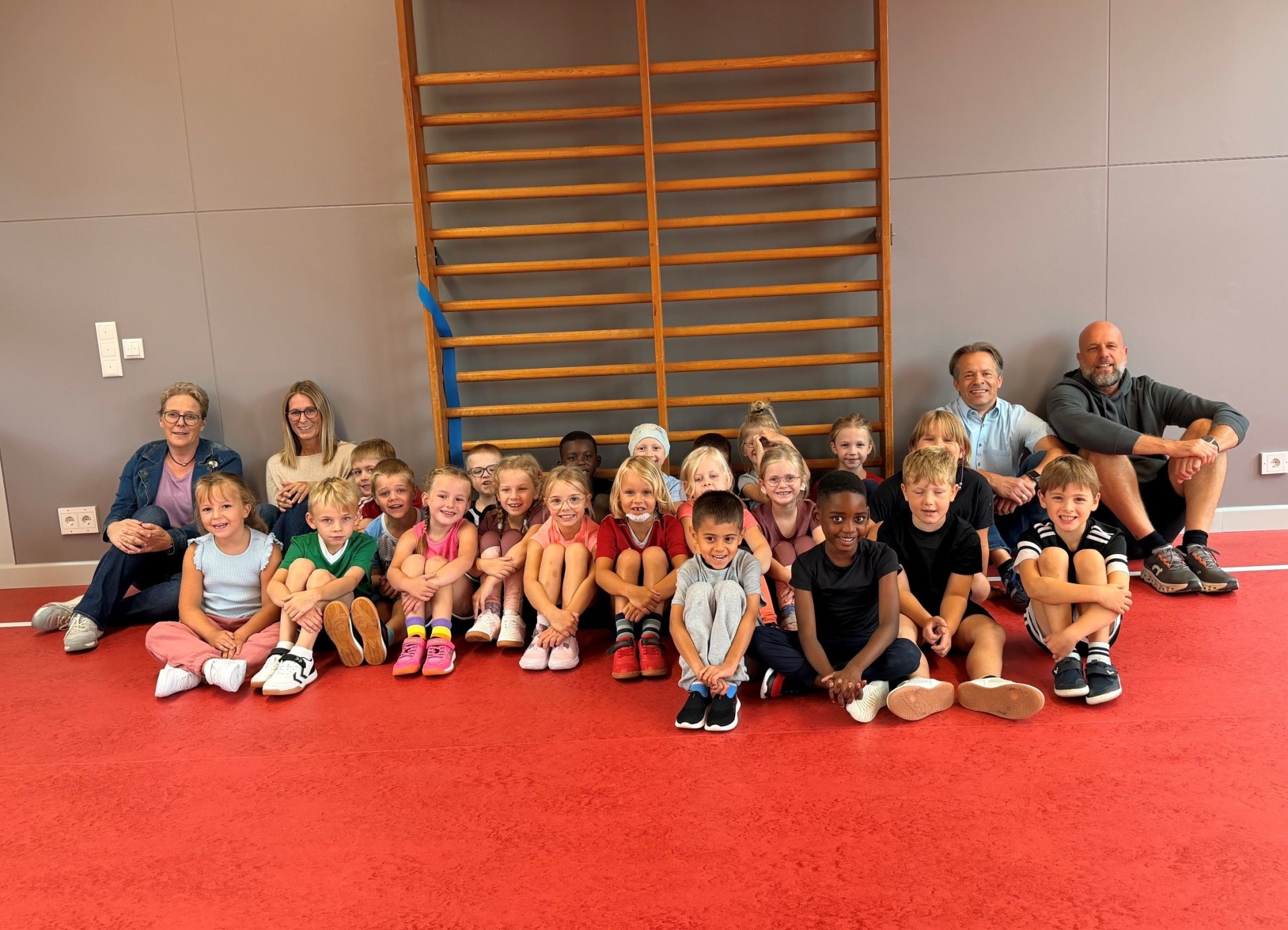 Kinder sitzen auf dem Boden in der Sporthalle der Grundschule Atzelgift-Streithausen