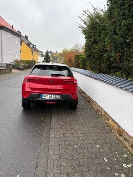 Ein rotes parkendes Auto auf einem Gehweg