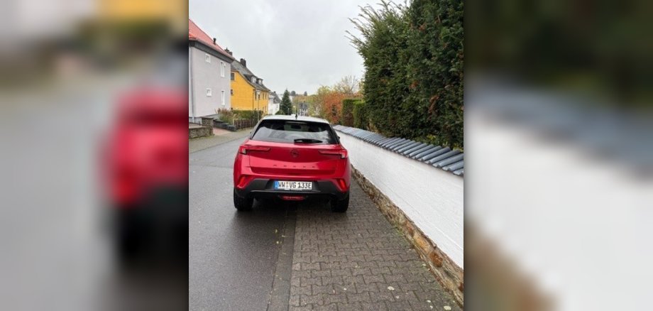 Ein rotes parkendes Auto auf einem Gehweg