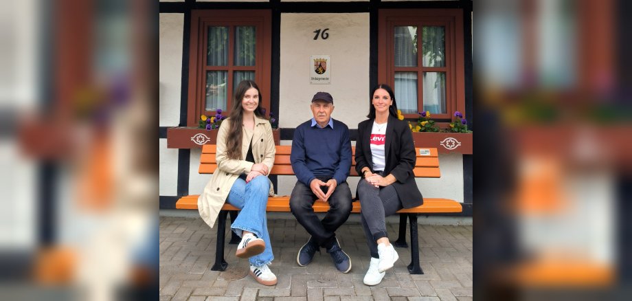 Gleichstellungsbeauftragte Alice Basar mit ihrern Stellvertreterin Michelle Gastall und Ortsbürgermeister Roland Müller sitzen auf der orangenen Bank