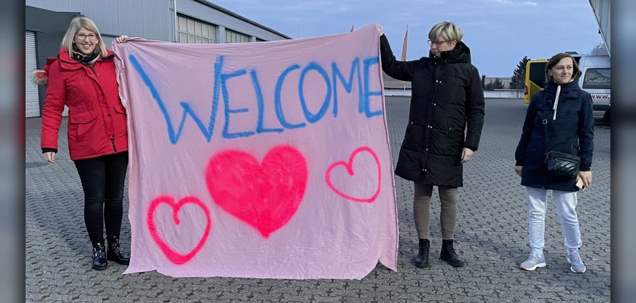 Menschen mit einem Welcome Plakat in der Hand