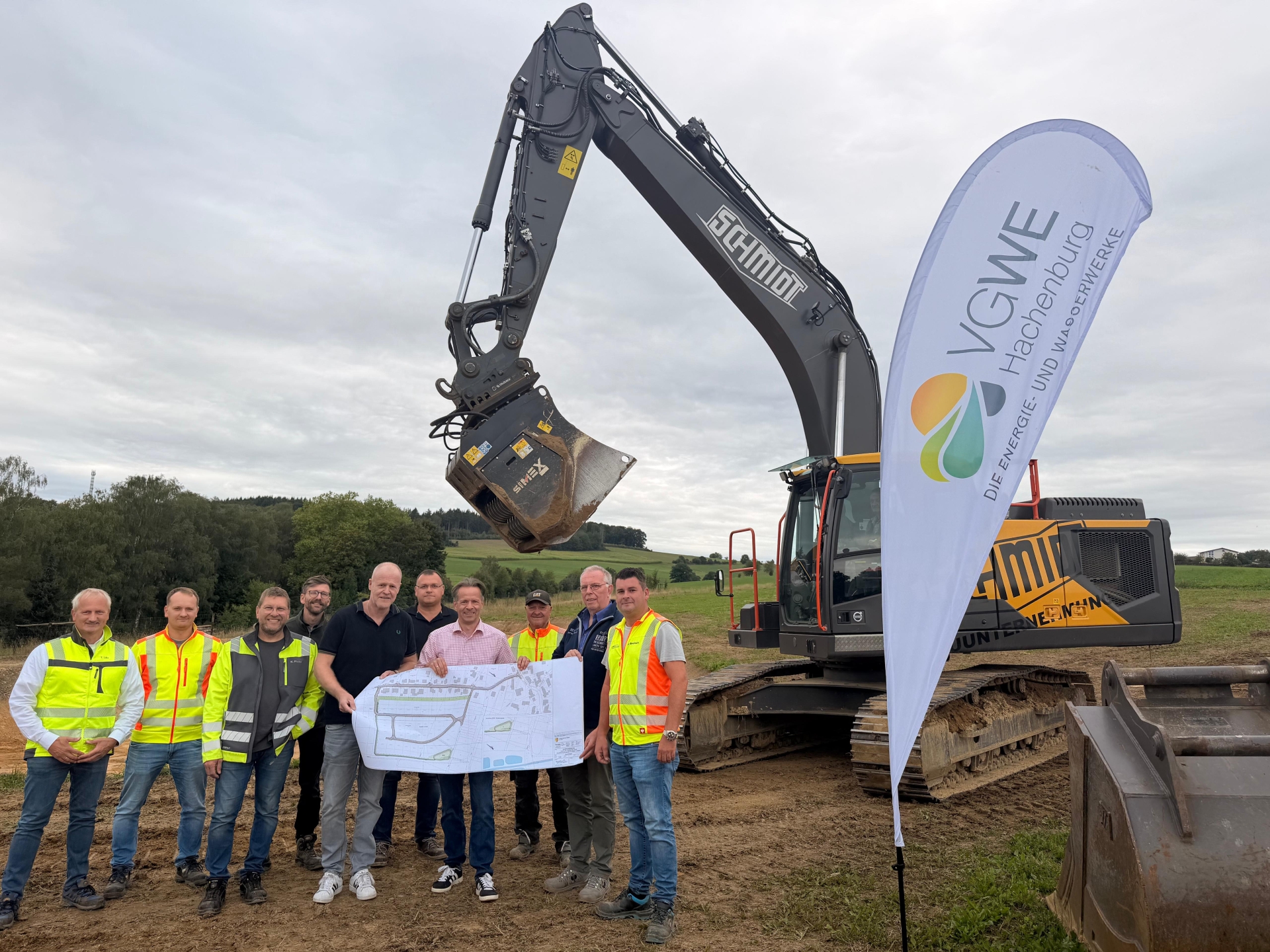 Erster Beigeordneter Marco Dörner, stellvertretender technischer Werkleiter Torsten Löhr, Bauingenieur Ronny Strunk und Ortsbürgermeister Peter Enders zusammen mit Vertretern des Bauunternehmens Robert Schmidt sowie dem Planungsbüro Gewatec beim zukünftigen Neubaugebiet in Hattert