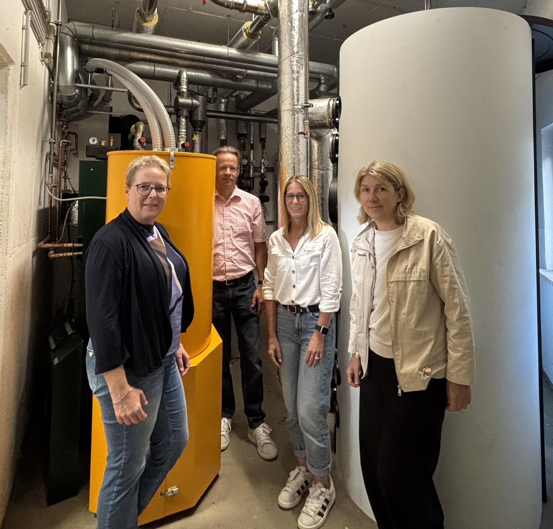 Erster Beigeordneter Marco Dörner, Leiterin des Fachbereichs Bildung und Soziales Kirsten Burbach sowie Ingenieurin Katrin Lück gemeinsam mit Schulleiterin Sandra Hummer vor der neuen Heizungsanlage 