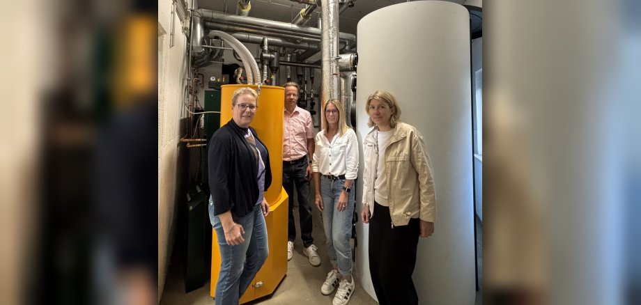 Erster Beigeordneter Marco Dörner, Leiterin des Fachbereichs Bildung und Soziales Kirsten Burbach sowie Ingenieurin Katrin Lück gemeinsam mit Schulleiterin Sandra Hummer vor der neuen Heizungsanlage 